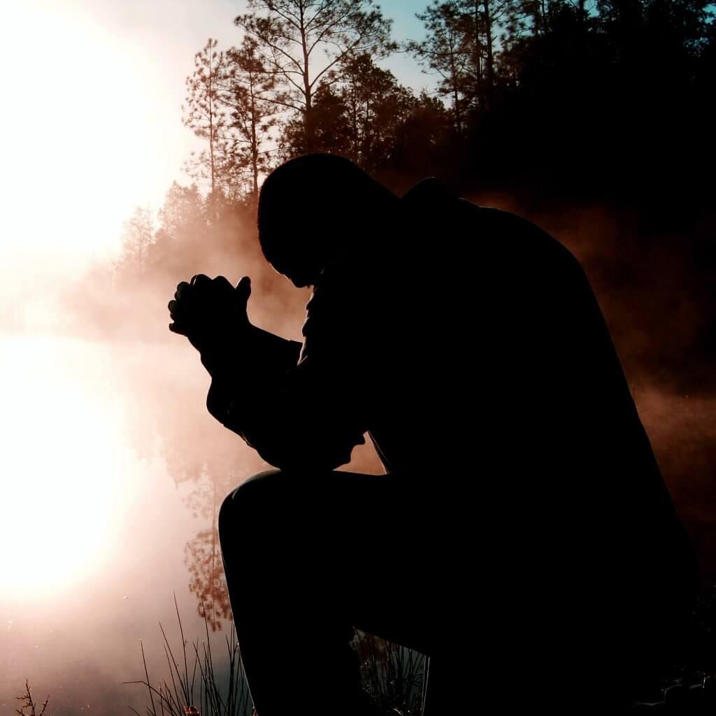 man kneeling next to lake
